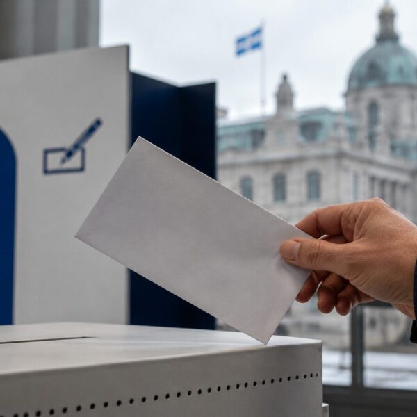 Votante depositando un sobre en una urna electoral de Quebec